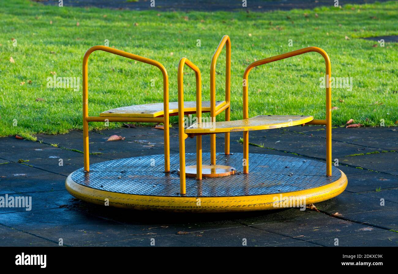 A small children`s playground roundabout with a safety surface surround